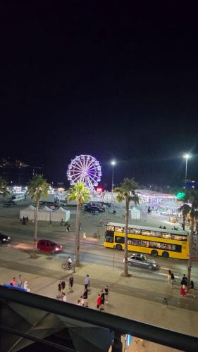 a yellow bus in a parking lot with a ferris wheel at Alba Suites in Vlorë