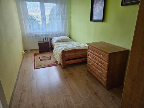 a bedroom with a bed and a dresser and a window at Pokoje do wynajęcia in Szczebrzeszyn