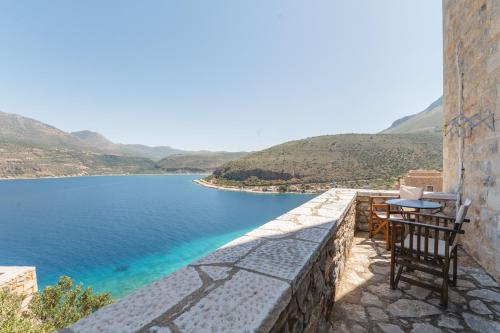 a balcony with a table and chairs overlooking a body of water at Limeni Village in Limeni