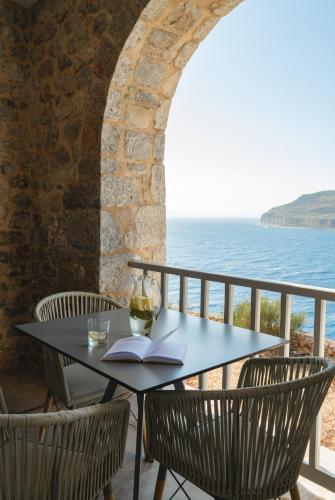 a table with a glass of wine and a book at Limeni Village in Limeni