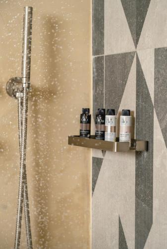 a bathroom with a shower with four shampoo bottles on a shelf at Limeni Village in Limeni