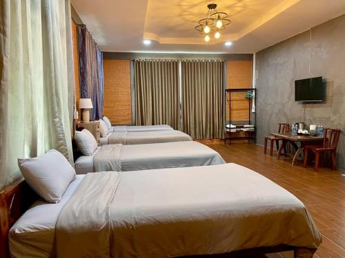 a hotel room with three beds and a television at MRK Resort & Massage in Lop Buri