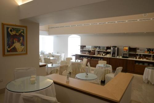 a restaurant with white tables and chairs and a kitchen at Albergo Italia in Matera