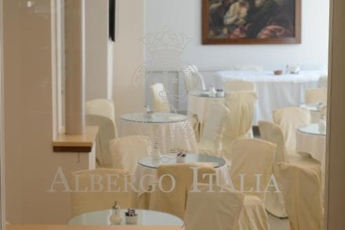 a room with white chairs and a large vase at Albergo Italia in Matera