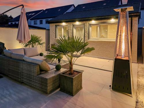 a patio with a couch and a tree and an umbrella at Alex Court in Leixlip