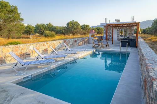 a pool with chaise lounge chairs next to a stone wall at Villa Arti in Haraki