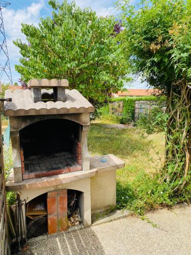 an outdoor brick oven in a yard with a tree at Maison propre et calme à 5 min du Futuroscope in Chasseneuil-du-Poitou