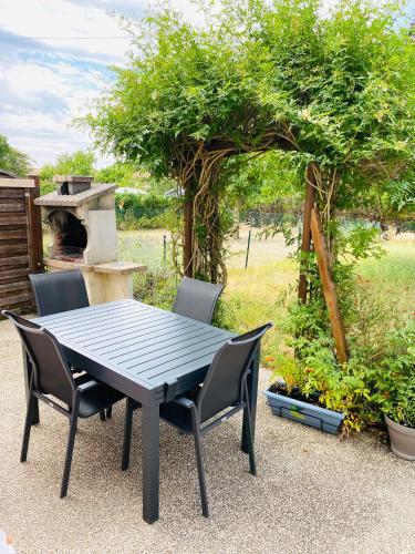 a black table and chairs in a yard with a grill at Maison propre et calme à 5 min du Futuroscope in Chasseneuil-du-Poitou