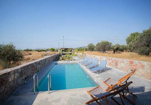 a swimming pool with lounge chairs next to a stone wall at Villa Arti in Haraki