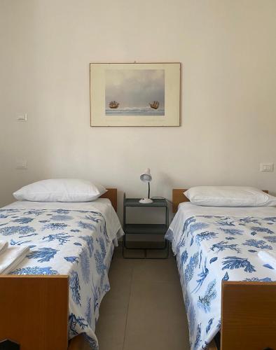 a bedroom with two beds and a picture on the wall at MAISON ANZIO E ROSA in Ravenna