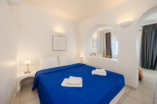 a white bedroom with a blue bed with towels on it at Kastro Suites in Fira