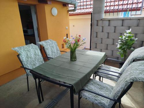 a table with chairs and a vase of flowers on it at Apartmán 480 Vino Strýček in Velké Bílovice