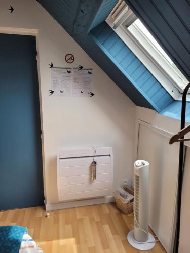 une chambre mansardée avec un radiateur blanc et un plafond bleu dans l'établissement Les Hirondelles à 5 mn de l' aeroport, à Beauvais