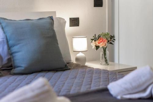 a bed with a vase of flowers and a lamp at Porta Torre - Guest Suite in Como