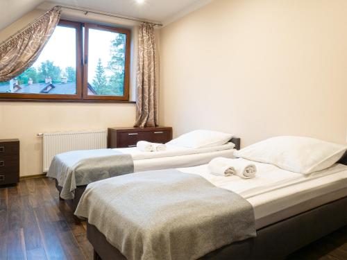 two beds in a room with a window at Dolina Leśnicy SKI & SPA Resort in Brenna
