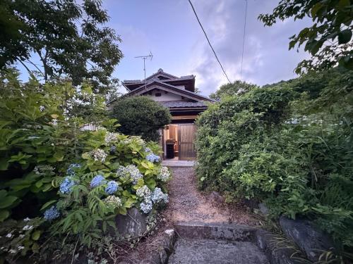 a house with a pathway leading to a house with flowers at 高島市一棟貸切貸別荘グループファミリーok 大人数でご利用だとお得連泊がお得BBQ可能自転車無料利用可ペット可 in Takashima