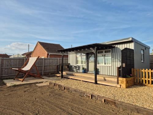 a small house with a deck and a chair at Zoila's Rest - A self-contained studio in Spalding