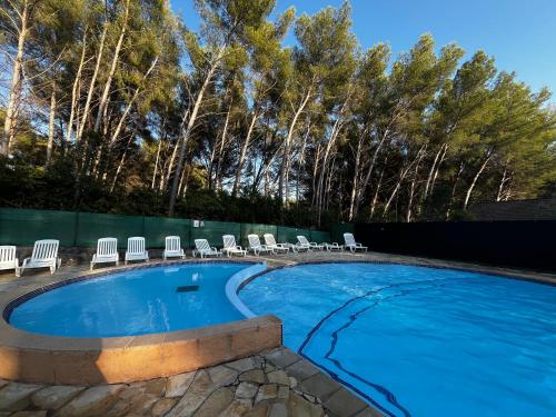une grande piscine avec des chaises longues et des arbres dans l'établissement Charmant studio Terrasse Piscine, à Sanary-sur-Mer