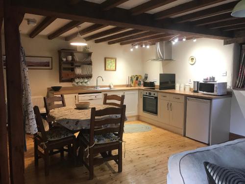 a kitchen with a table and chairs and a kitchen with a sink at Stone Barn - B6063 in Pooley Bridge