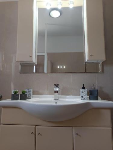 a bathroom sink with a mirror and a sink at Villa Eleni in Kypséli