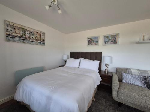 a bedroom with a large white bed and a chair at Zoila's Rest - A self-contained studio in Spalding