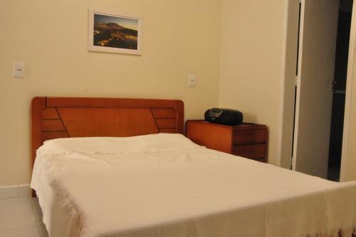 1 dormitorio con cama blanca y cabecero de madera en No Coração de COPACABANA, en Río de Janeiro