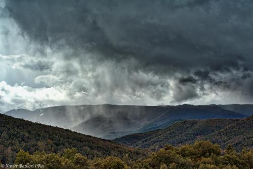 a cloudy sky over a mountain range with trees at Fonda Finet in Sant Felíu de Pallarols