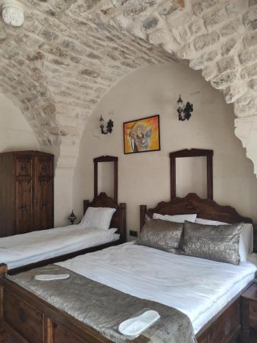 two beds in a bedroom with a stone wall at Babilyon Otel in Urfa