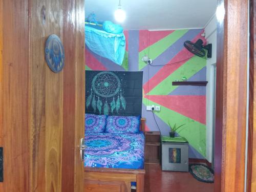 a bedroom with a bed with a colorful wall at Shanti Guest House Ella in Ella