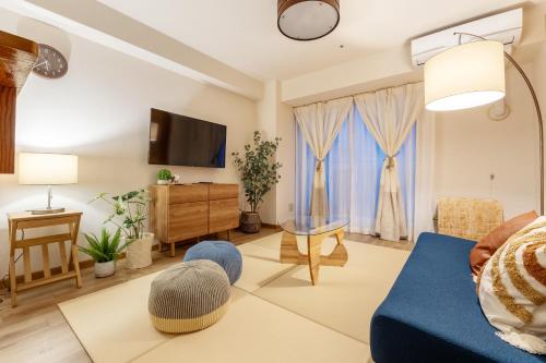 a living room with a blue couch and a tv at Cozy Stay Sapporo Central Nakajima in Toyohira