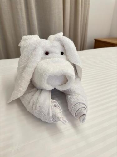 a white towel animal sitting on a bed at COSMOS Studios Iraklia in Irakleia