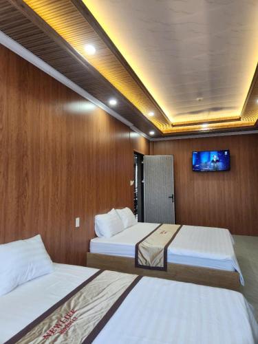 a bedroom with two beds and a tv on the wall at New Life Homestay in Phan Thiet