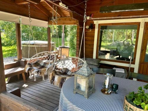 a porch of a log cabin with a table and swings at Cozy Cabin with a Beautiful Sauna Near Lake in Lappeenranta