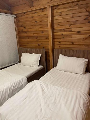 two beds in a room with wooden walls at اكواخ وشاليهات جولدن الفندقية in Jeddah