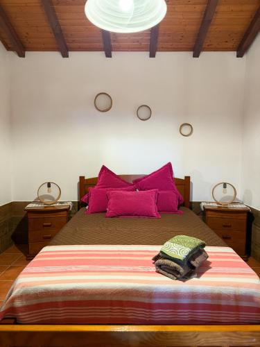 a bedroom with a large bed with pink pillows at Monte dos Touris in Santiago do Cacém