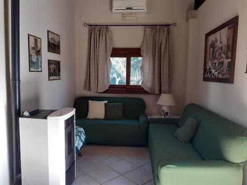 a living room with a green couch and a window at Villetta BLUE GARDEN in Sonnino