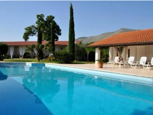 a blue swimming pool with chairs and a house at Villetta BLUE GARDEN in Sonnino