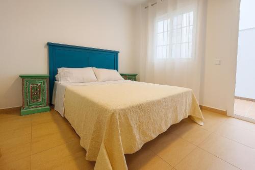 a bedroom with a bed with a blue headboard and a window at Apartamento Ría Punta Umbría in Punta Umbría