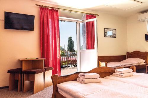 a bedroom with two beds and a window with red curtains at Hotel Zámeček in Mikulov