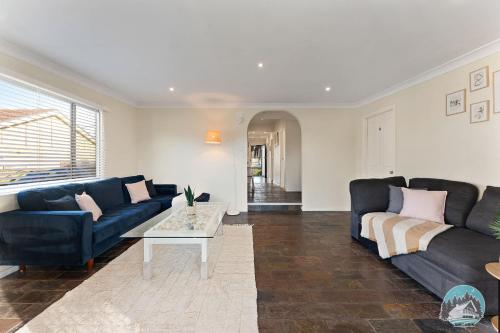 a living room with two blue couches and a table at Spacious 4BR House Near Kingswood & Penrith CBD in Kingswood