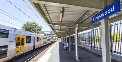 a train station with people sitting on a platform next to a train at Spacious 4BR House Near Kingswood & Penrith CBD in Kingswood