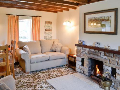 a living room with a couch and a fireplace at Swaledale Cottag in Caldbeck