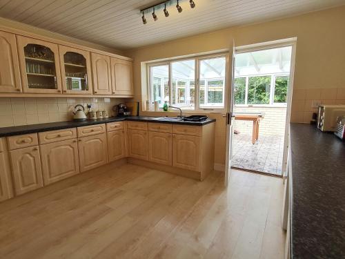 a large kitchen with wooden cabinets and a large window at The Nest in Aylsham
