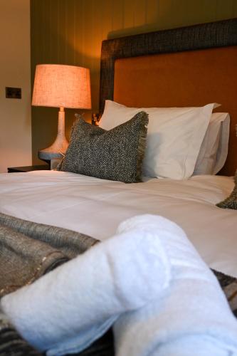 a bed with white sheets and pillows and a lamp at The Apple Inn in Lucker