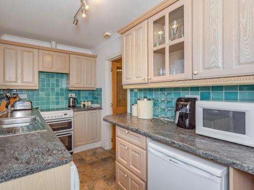 a kitchen with wooden cabinets and a white microwave at Chesnut Cottage in Banavie