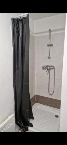 La salle de bains est pourvue d'une douche avec rideau de douche noir. dans l'établissement 2 pièces + Parking à 15 min de Paris, à Argenteuil