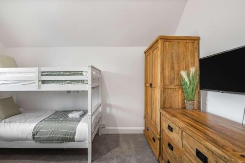 a bedroom with a bunk bed and a wooden dresser at The Roost Group - Brands Hatch 6 Bedroom Home in Fawkham