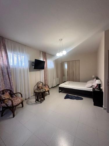 a bedroom with a bed and two chairs and a tv at Ktima Lena in Órmos