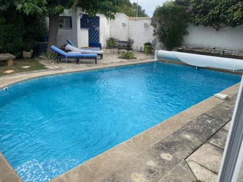 a large blue swimming pool with two blue chairs in it at VILLA MIREILLE CALME ARBOREE PISCINE SANS VIS A VIS SECURISEE in Morières-lès-Avignon
