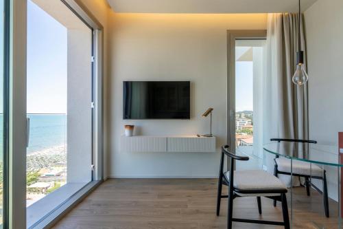 a living room with a dining table and a television at Opera Suite Hotel Pesaro in Pesaro